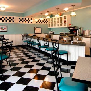 A retro-style diner with teal bar stools and a black-and-white checkerboard floor.