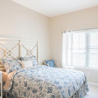 A cozy bedroom with natural light, featuring a well-made bed and elegant decor.