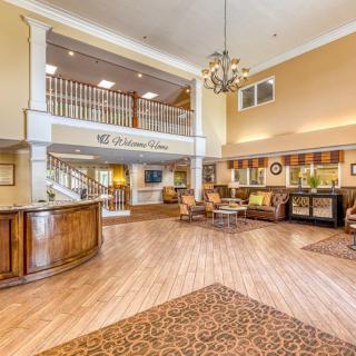 A spacious hotel lobby with a reception desk, comfortable seating area, and elegant chandelier.