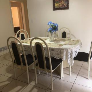 A cozy dining area with a round table, chairs, and a floral centerpiece.
