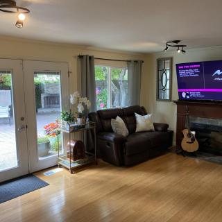 A cozy living room featuring a sofa, television, fireplace, and guitar with large French doors opening to the outside.