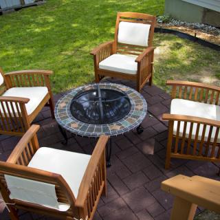 A cozy outdoor seating area with wooden chairs and a fire pit on a patio.