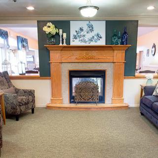 A cozy living room featuring a central fireplace with decorative elements on the mantel, surrounded by comfortable seating.