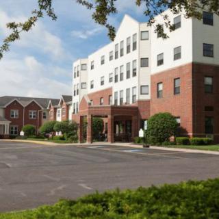 A view of a healthcare facility with a spacious parking area and landscaped surroundings.