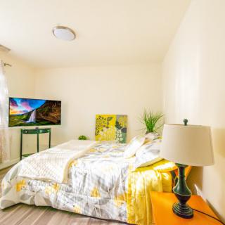A bright and cozy bedroom featuring colorful bedding, a television, and decorative artwork.