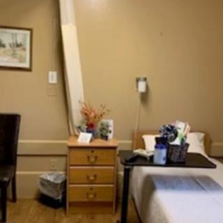 A hospital room with a bed, nightstand, and decor.