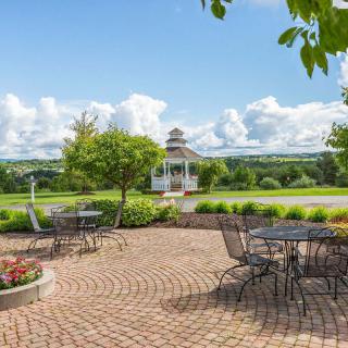 A scenic patio with outdoor seating overlooking a lush landscape and a gazebo in the distance.