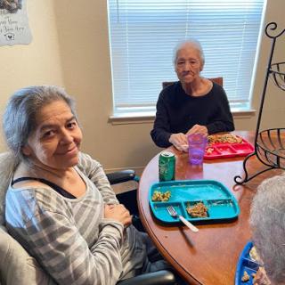 Two elderly women enjoying a meal together in a cozy setting.