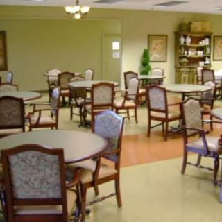 A spacious dining room with multiple round tables and upholstered chairs neatly arranged.