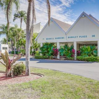 A sunny view of a tropical-themed building surrounded by palm trees and lush landscaping.