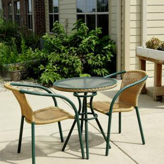 A cozy outdoor seating area featuring a glass table and two wicker chairs, perfect for enjoying a sunny day.