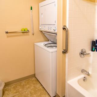 A compact bathroom with a stacked washer and dryer next to a bathtub.