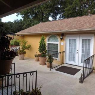 A cozy patio area with potted plants and a small house featuring French doors.
