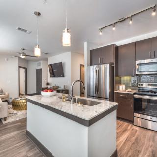 A modern kitchen with an island counter, stainless steel appliances, and sleek pendant lighting.