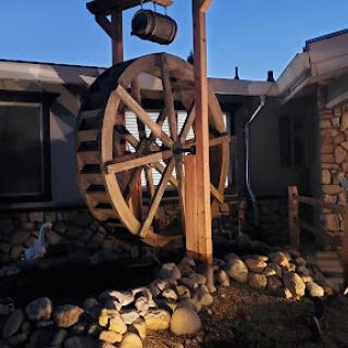 A beautifully crafted wooden water wheel as a decorative feature in a garden setting.