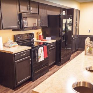A modern kitchen featuring dark cabinets, countertops, and various appliances.