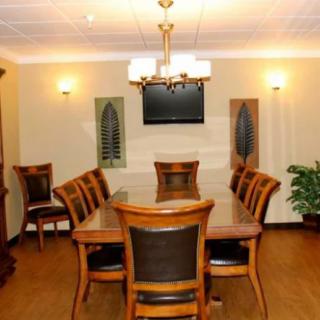A well-appointed conference room with a large meeting table and chairs, featuring a central lighting fixture and a wall-mounted television.
