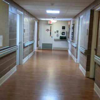 A quiet corridor in a hospital, featuring a well-lit environment and wooden flooring.