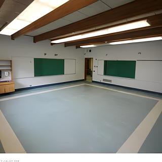 An empty classroom with chalkboards and exposed ceiling beams.