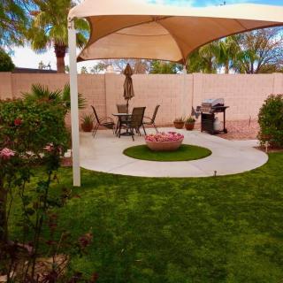 A well-maintained backyard featuring a shaded patio area with outdoor seating and lush green landscaping.