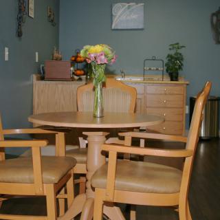 A cozy dining area featuring a wooden table surrounded by chairs, with a vase of colorful flowers as the centerpiece.
