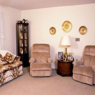 A cozy living room with two armchairs, a patterned sofa, and decorative elements on the wall.