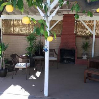 A cozy patio with outdoor seating, a fireplace, and lemon decorations under a shaded area.