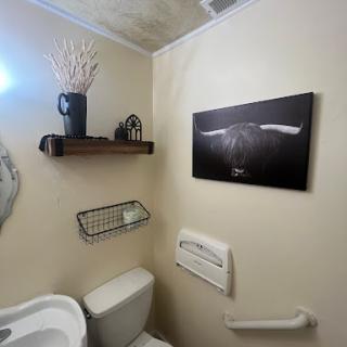 A cozy bathroom featuring stylish decor, including a shelf with plants and modern artwork on the wall.