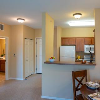 A modern apartment interior featuring a small kitchen with appliances and an adjacent dining area.