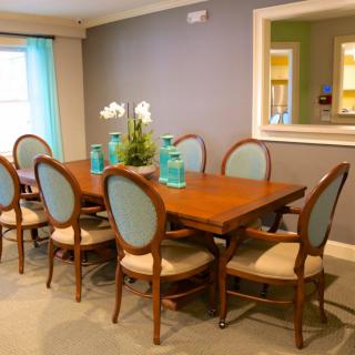 A modern dining room with a large wooden table surrounded by upholstered chairs and decorative vases.