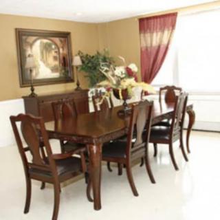 A well-decorated dining room with a wooden table and chairs, adorned with artwork and elegant curtains.