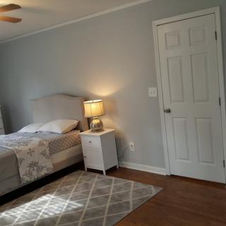 A minimalist bedroom with a bed, nightstand, and lamp next to a closed door.