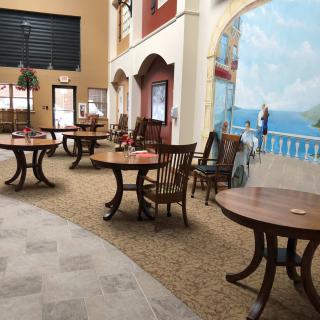An interior view of a restaurant with wooden tables and chairs, featuring a mural on the wall.