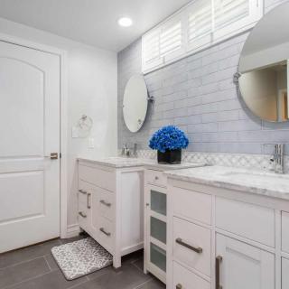 A modern bathroom featuring a double vanity with circular mirrors, decorated with a vase of blue flowers.