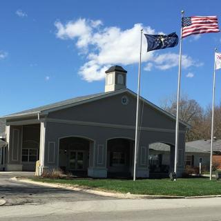 A building with several flags in front of it under a partly cloudy sky.