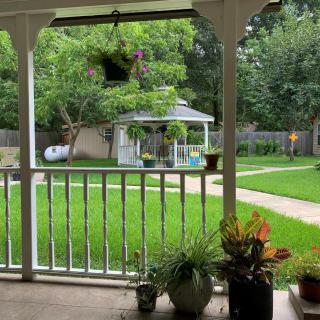 A serene view from the porch overlooking a lush garden with a gazebo.