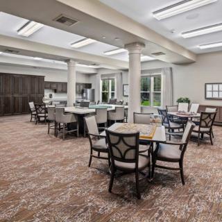 A spacious and well-lit dining area with several tables and chairs, featuring skylights and large windows.