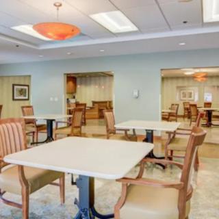A spacious dining area with neatly arranged tables and chairs, featuring bright overhead lighting.