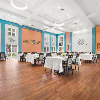 A spacious and modern dining area with neatly arranged tables and chairs, featuring colorful walls and a wooden floor.