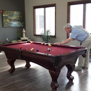 A person playing billiards on a red pool table in a game room.