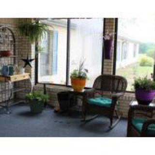A cozy sunroom with rocking chairs and various potted plants by a large window.