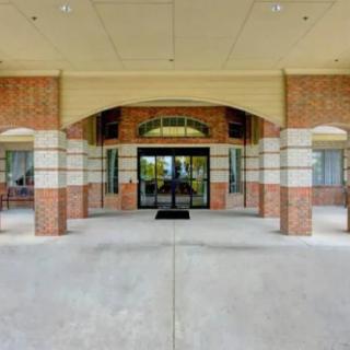 A brick building entrance with a glass door and overhang.