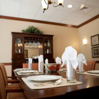 An elegantly set dining room table with neatly folded napkins and a wooden cabinet in the background.