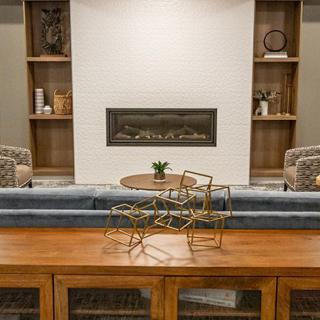 A modern living room with a central fireplace, stylish shelving, and comfortable seating.