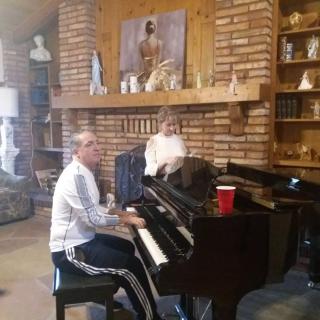 A person playing the piano in a cozy living room with brick walls and various decorations.