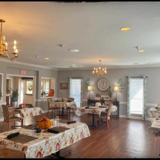 A cozy dining room with elegantly set tables, chandeliers, and tasteful decor.