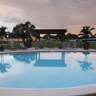 A serene outdoor swimming pool with surrounding patio furniture and a cloudy evening sky.