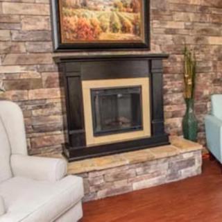 A cozy living room with a modern fireplace, adorned with a brick wall backdrop and comfortable seating.