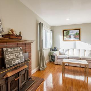 A cozy living room with a fireplace, sofa, and wooden flooring, featuring elegant decor and natural lighting.