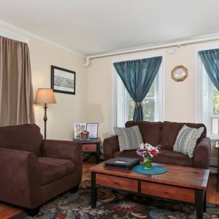 A cozy living room with a brown sofa and armchair, complemented by blue curtains and a wooden coffee table.